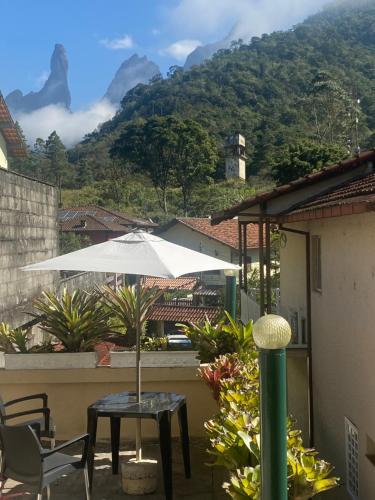 einen Tisch mit einem Sonnenschirm auf einem Balkon mit einem Berg in der Unterkunft Chalé Luxuoso de Hospedes in Teresópolis