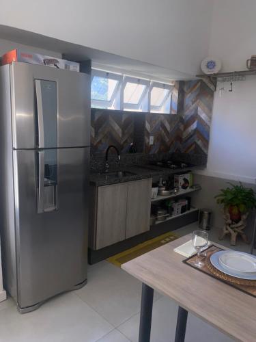 eine Küche mit einem Kühlschrank aus Edelstahl und einem Tisch in der Unterkunft Chalé Luxuoso de Hospedes in Teresópolis
