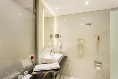 a white bathroom with a sink and a mirror at Calypso Palace in Faliraki