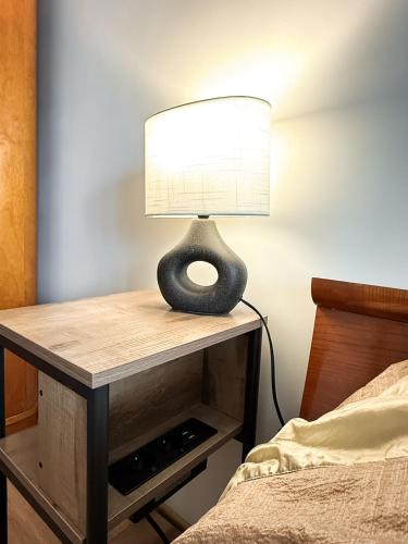a lamp on a table next to a bed at Baltic Breeze apartment in Liepāja