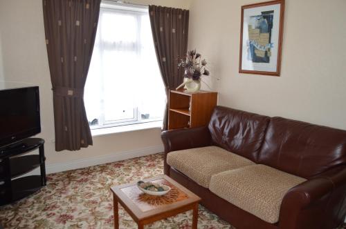 a living room with a brown leather couch and a window at Welcome Holiday Flats in Skegness