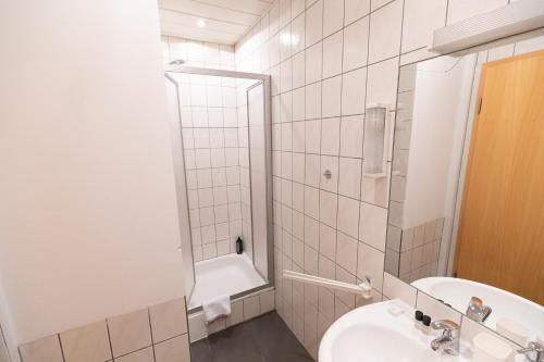 a white bathroom with a sink and a shower at Hotel Dernbach in Dernbach
