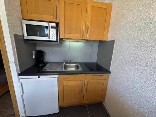 une petite cuisine avec un évier et un micro-ondes dans l'établissement Charmant studio aux Ménuires, proche des pistes, équipé pour 3 personnes avec balcon nord-ouest - FR-1-452-173, aux Menuires