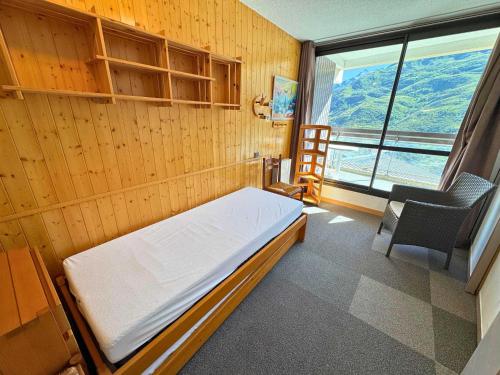 Cette chambre comprend un lit, une chaise et une fenêtre. dans l'établissement Duplex cosy pour 10 personnes à Reberty 1850, au pied des pistes, avec balcon et parking couvert - FR-1-452-239, aux Menuires