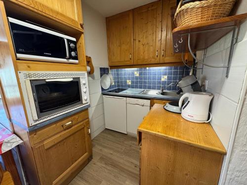une petite cuisine avec un évier et un micro-ondes dans l'établissement Appartement Confort 4 Pers., Balcon Sud-Ouest, Reberty 1850, Proche Pistes et Commerces - FR-1-452-261, aux Menuires