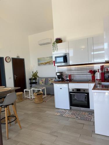 a kitchen with white appliances and a table and a table at Villa Estrelitzia sea view 1 à 6 p in Lomba