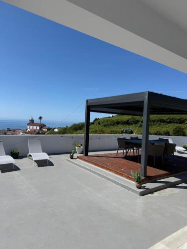 a pavilion with a table and chairs on a roof at Villa Estrelitzia sea view 1 à 6 p in Lomba