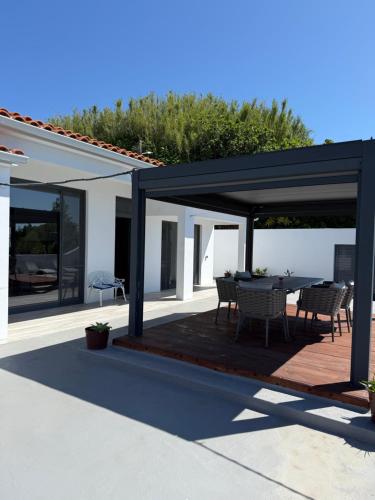 a patio with a table and chairs under a pavilion at Villa Estrelitzia sea view 1 à 6 p in Lomba