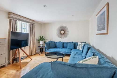 a living room with a blue couch and a tv at Costal Retreat with Garden & BBQ in Lymington