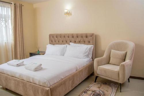 a bedroom with a large bed and a chair at Serenity Stays-Venus suite in Nakuru