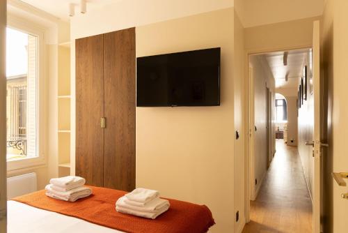 Cette chambre comprend un lit avec des serviettes et une télévision à écran plat. dans l'établissement Jardin des Plantes - Amazing 2BR 4P apartment, à Paris