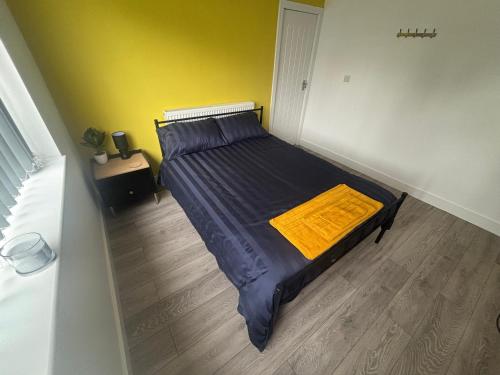 a bedroom with a bed with a yellow blanket on it at Kane's Place in Birkenhead
