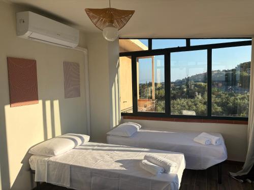 two beds in a room with a large window at Civico 20 la casa di Nina in Reggio Calabria