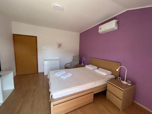 a bedroom with a bed with a purple wall at Apartment Kix in Rab