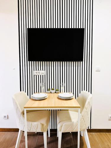 a dining room table with chairs and a television on a wall at Penthouse Studio Borovi in Divčibare
