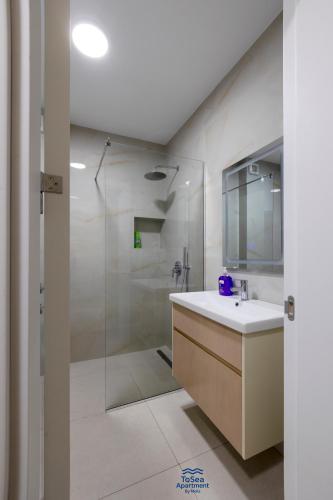 a bathroom with a shower and a sink and a mirror at ToSea Apartment by Melia in Lalzit Bay