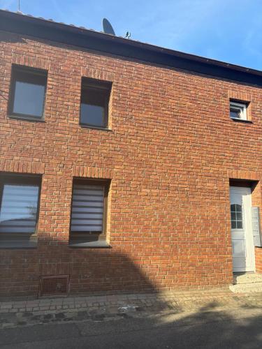 a brick building with three windows and a white door at Monteurwohnung-Ferienapartment in Euskirchen