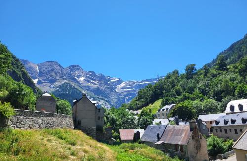 a village on a hill with mountains in the background at Séjour d'Exception - Villa 4 Suites Vue Cascade in Gavarnie