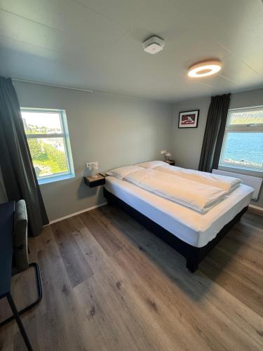 a bedroom with a large bed and two windows at Hótel Gerpir in Neskaupstaður