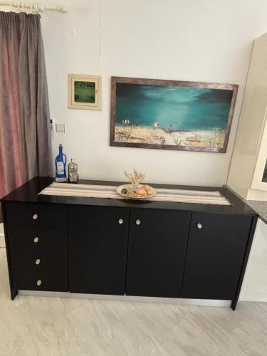 a black cabinet in a room with a painting on the wall at Pebble Sea House in Orfánion