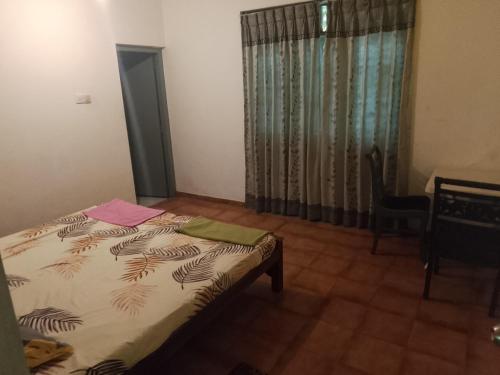 a bedroom with a bed and a desk and a window at kandy in Talawatuhenpita North