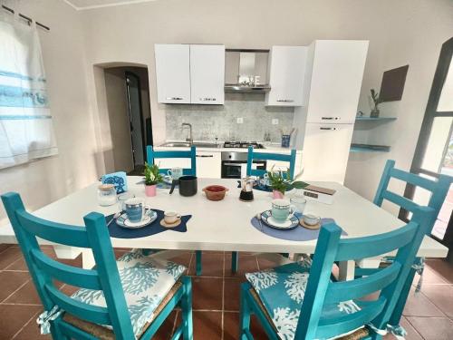 a kitchen with a table with blue chairs and a kitchen with white cabinets at Casa Antele in Quartu SantʼElena