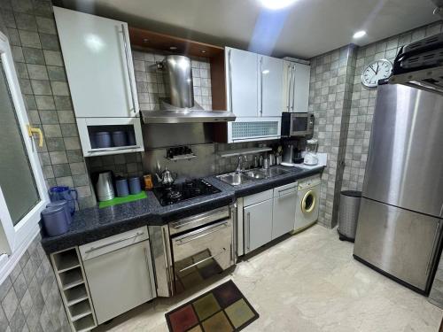 a kitchen with white cabinets and stainless steel appliances at Yildirim Hotel Apartments in Oulad Akkou