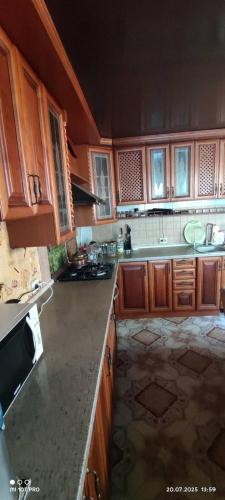 Una cocina con gabinetes de madera y encimera. en Дом у моря, en Chornomorsk