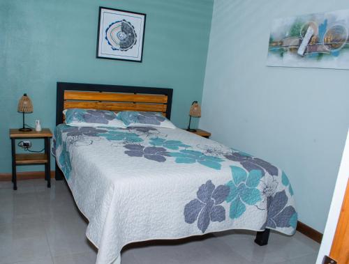 Un dormitorio con una cama con una pared azul. en Mi Barrio, en Cartago