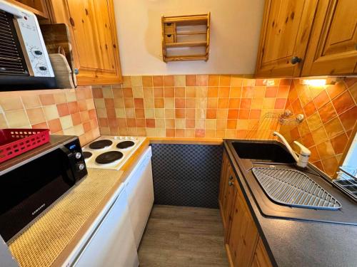 Il comprend une petite cuisine équipée d'une cuisinière et d'un évier. dans l'établissement Résidence Origanes - Appartement pour 10 proche des pistes aux Ménuires MAE-4324, aux Menuires