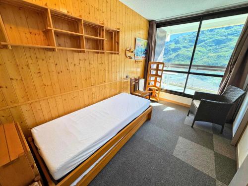 Cette chambre comprend un lit, une chaise et une fenêtre. dans l'établissement Résidence Origanes - Appartement pour 10 proche des pistes aux Ménuires MAE-4324, aux Menuires