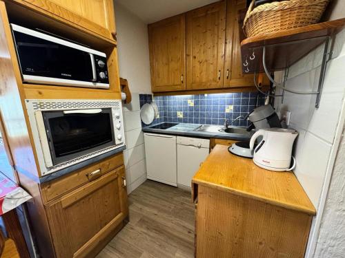 - une petite cuisine avec des placards en bois et un four micro-ondes dans l'établissement Résidence Median - Appartement équipé pour 4 personnes aux Ménuires MAE-5544, aux Menuires
