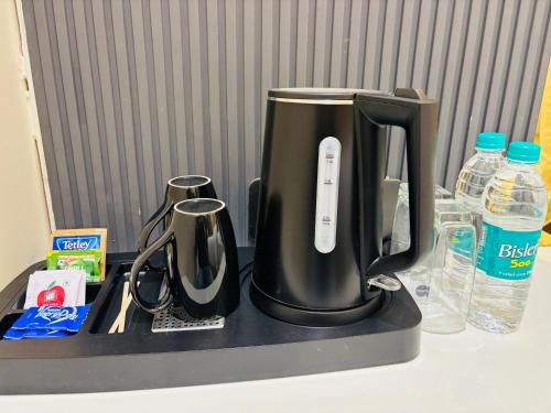 a black coffee maker on a counter with bottles of water at Hotel Sun-n-Moon in Shirdi