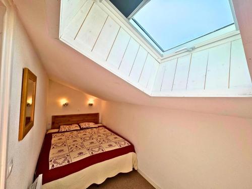 une chambre avec un lit et une lucarne dans l'établissement Résidence Necou - Grand duplex rénové pour 6 personnes MAE-3904, aux Menuires