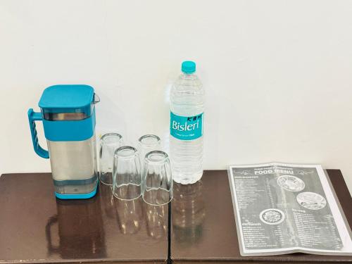 a bottle of water sitting next to glasses on a table at Hotel Kedar Bliss Heaven inn in Gaurikund
