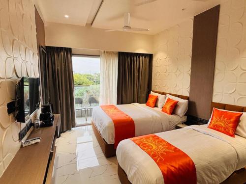 a hotel room with two beds and a television at Hotel Sun-n-Moon in Shirdi