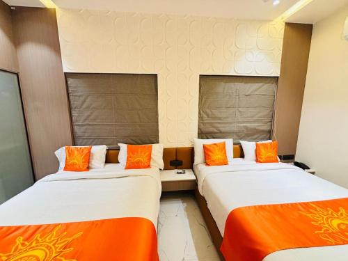 two beds in a hotel room with orange pillows at Hotel Sun-n-Moon in Shirdi