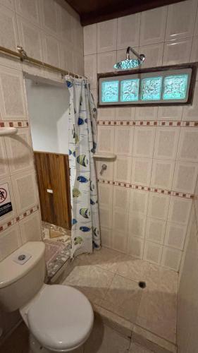 a bathroom with a toilet and a window at Hostal CASA COLIBRI MINCA in Minca