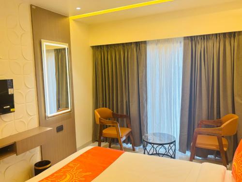 a hotel room with a bed and two chairs at Hotel Sun-n-Moon in Shirdi