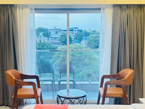 a room with two chairs and a table and a window at Hotel Sun-n-Moon in Shirdi