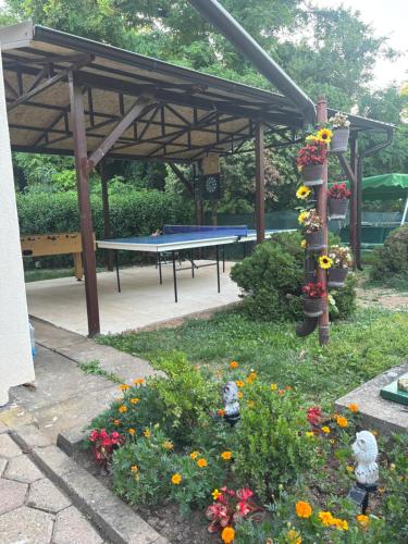 a picnic shelter with a ping pong table and flowers at Vikendica Fruškogorski kutak - Fruška Gora in Čerević
