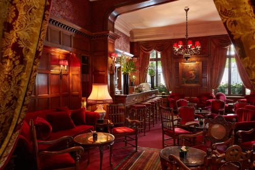 a room with a bar with red chairs and tables at Hôtel Raphael in Paris