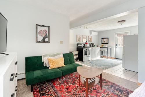 a living room with a green couch and a kitchen at Properties by Menjivar in Beverly