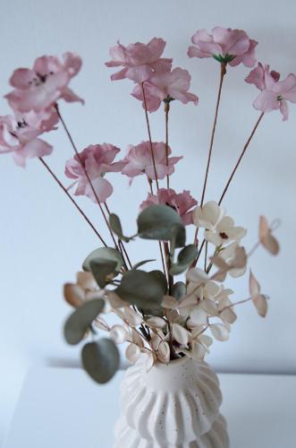 a white vase with pink flowers in it at Vakantiewoning Ten Huyze Bucholt met tuinsauna in Bocholt