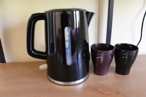 a black coffee pot sitting on a table with two cups at Guest Suite in Maple Ridge in Maple Ridge District Municipality