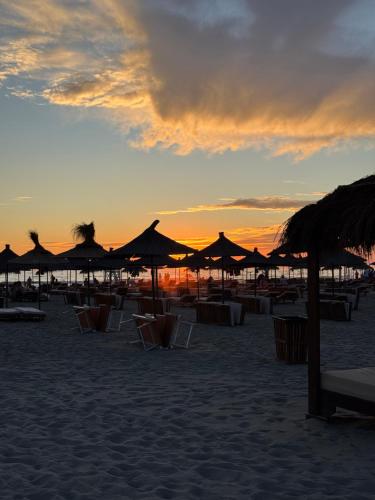 a group of chairs and umbrellas on the beach at sunset at ToSea Apartment by Melia in Lalzit Bay