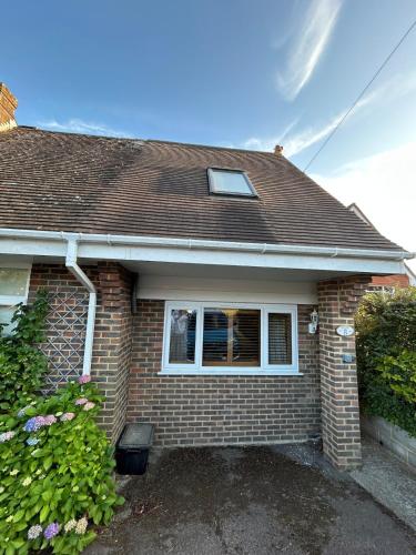 a brick house with a window and bushes at Beejou in Sedlescombe
