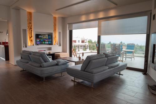 a living room with two couches and a balcony at White Sand Loutraki Villa - Sea View in Loutraki