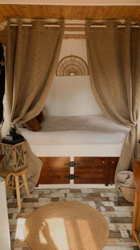- une chambre avec un lit doté de rideaux et d'un tapis dans l'établissement La roulotte d'Elicie, à Saint-Agnan-sur-Loire