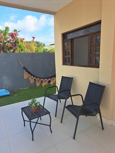 three chairs and a table on a patio at Charmosa Casa de Praia in Pitimbu